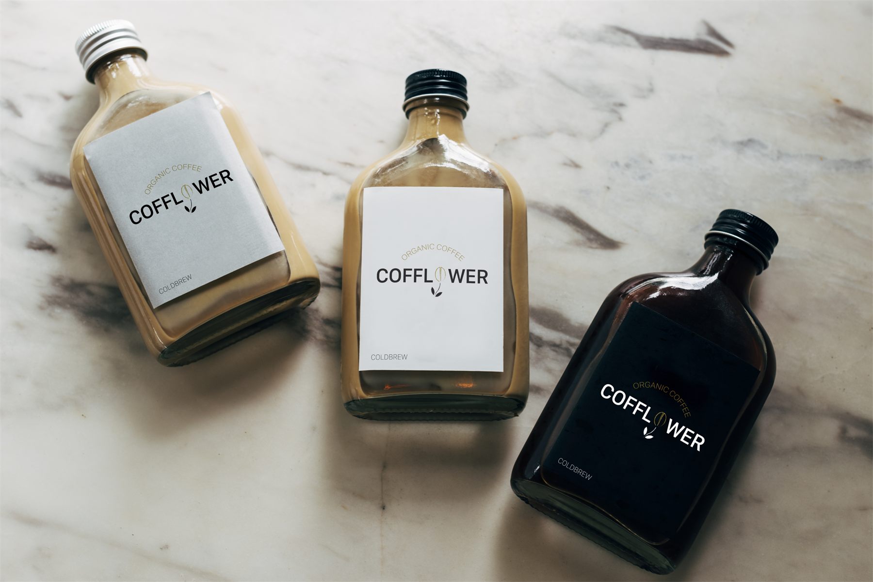 Tri fľaše cold brew kávy s etiketami Cofflower na mramore